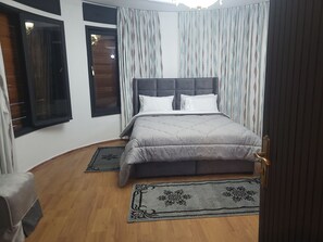 Une chambre à coucher avec un lit, des rideaux, une fenêtre et une porte.
