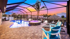 Un espace extérieur abrité comprenant une piscine, un jacuzzi et un coin salon avec des chaises et des tables.