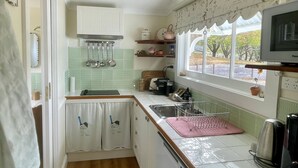 A compact kitchen with a sink, a stove, and a window with a view of the outdoors. - Gorgeous cottage in the heart of the picturesque Huon Valley. (Castle Forbes Bay)