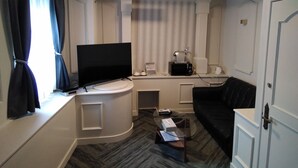 A compact living area with a flat-screen TV, a coffee maker, and a microwave on a countertop.
