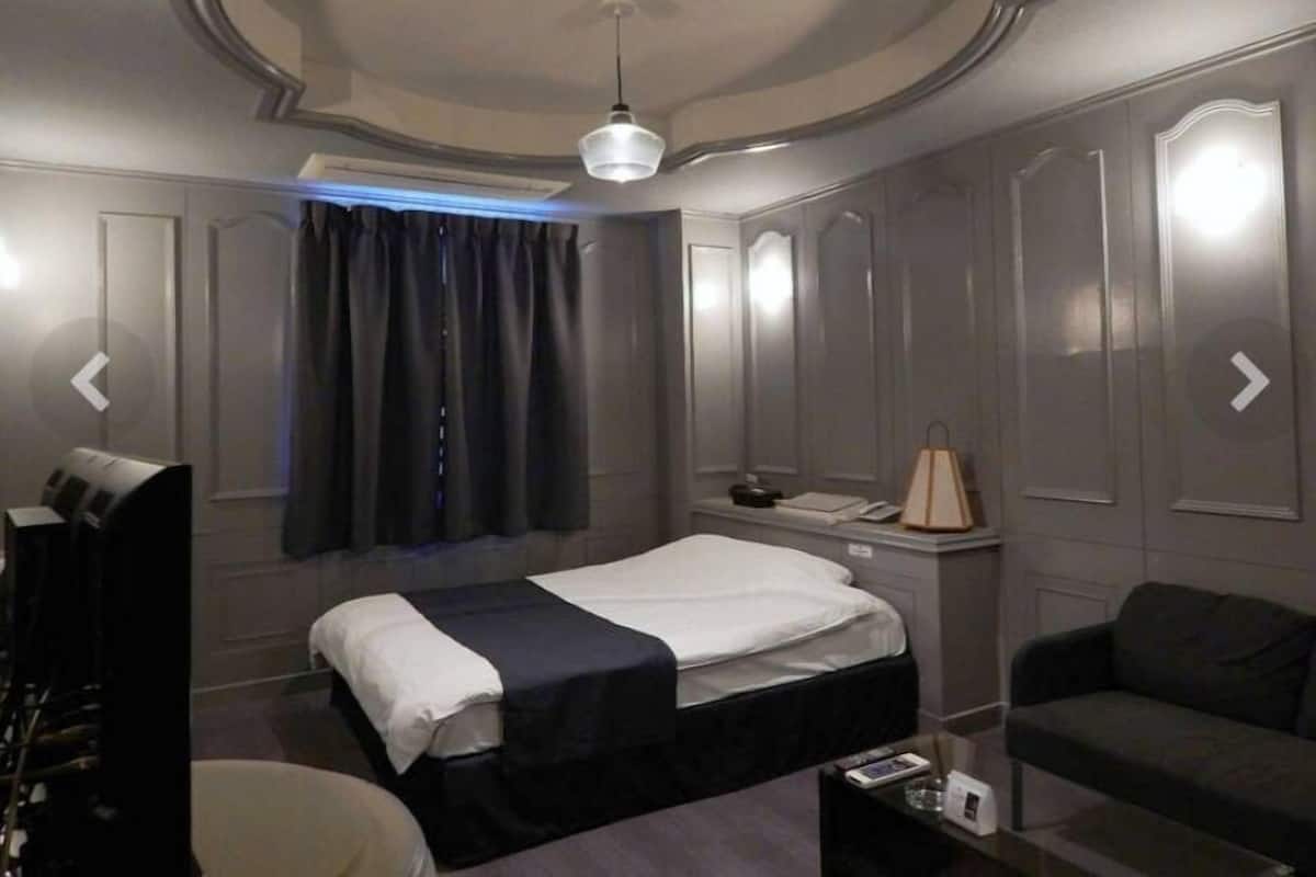 Une chambre d’hôtel moderne équipée d’un lit, d’un canapé, d’une petite table et d’un bureau.