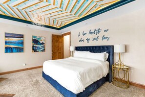 Un dormitorio con una cama, una pared con una cita y dos cuadros.