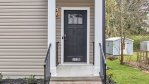 A front door with a number plate, a small porch with steps, and a garden area with a shed and tree. - Pet-Friendly 2BR Greer Home, King Beds & Fire Pit (Greer)