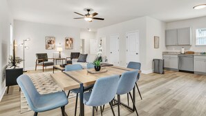 A modern living room with a dining area, kitchen, and a ceiling fan. - Family & Pets Welcome: 2BR in DT Greer w/ Fire Pit (Greer)