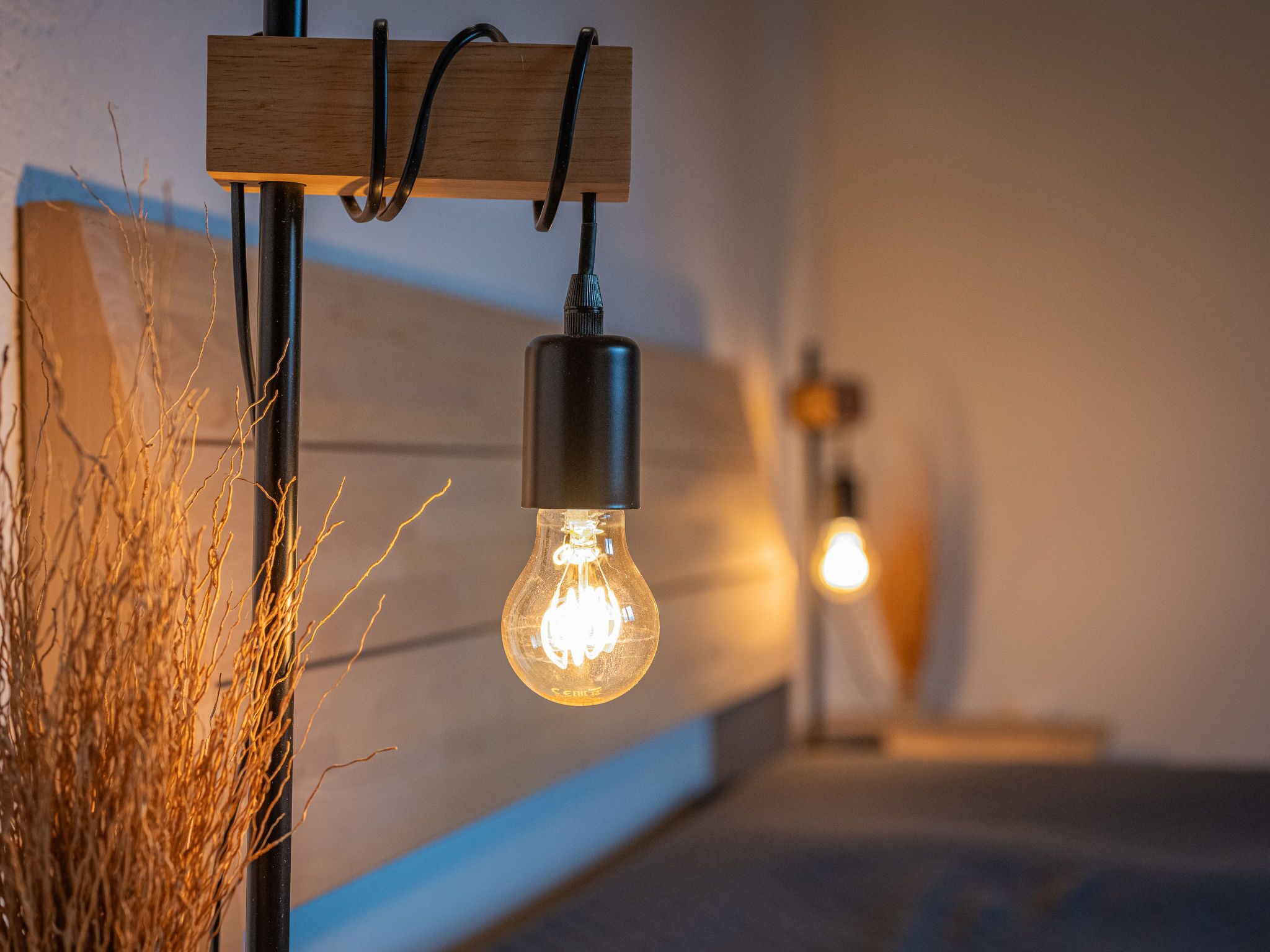 A hanging light bulb with a wooden mount and a black cord.