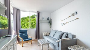 Un salon avec un canapé, un fauteuil, une table basse et un téléviseur.