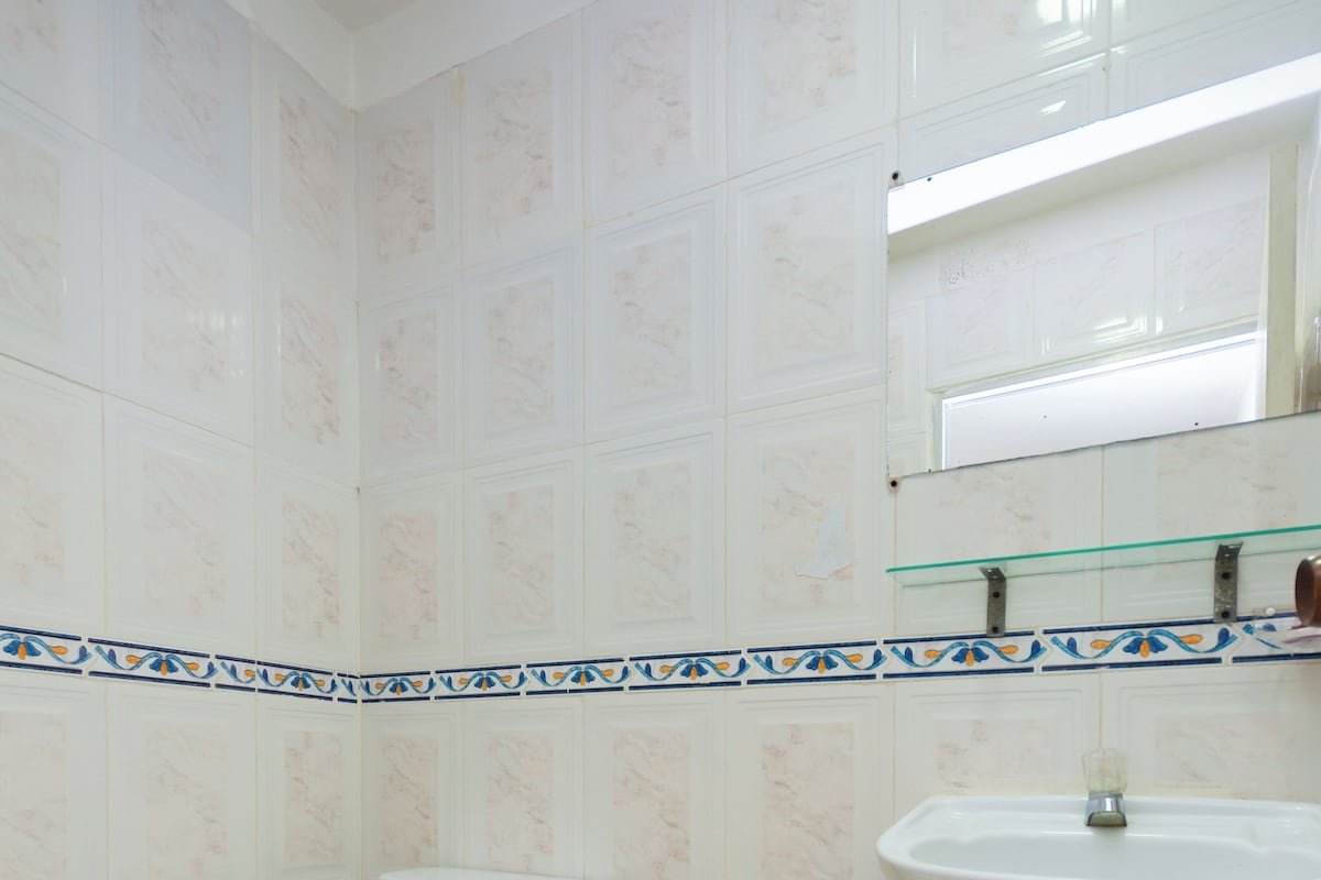 Un baño con inodoro, lavamanos y paredes de azulejos.