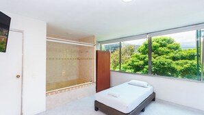 A modern bedroom with a large window, a walk-in shower, and a bed. - Hotel Villa Real (Medellín)