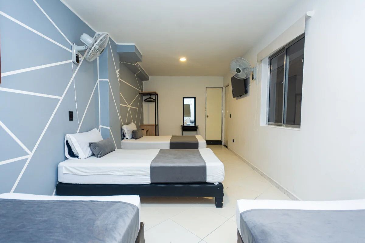 A hotel room with two beds, a mirror, a TV, and a window.
