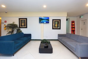 Un área de recepción con dos sofás, una mesa de centro y cuadros enmarcados en la pared.