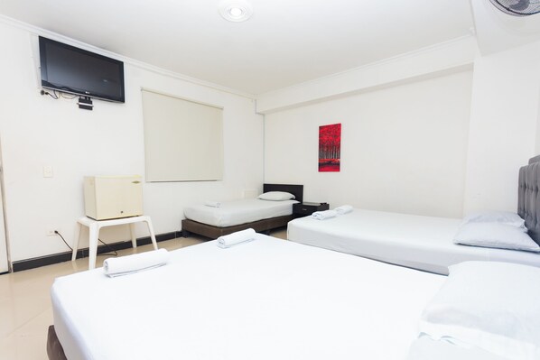 A hotel room with two single beds, a flat-screen TV mounted on the wall, a small table, and a red artwork on the wall. - Hotel Villa Real (Medellín)
