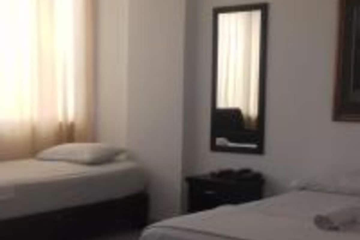 Un dormitorio con dos camas, una mesita de noche y un espejo en la pared.