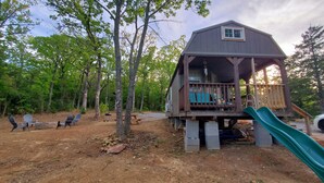 Una cabaña con terraza, tobogán y mobiliario exterior.