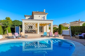 A modern villa with a swimming pool, outdoor seating, and a well-maintained garden.