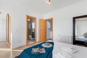 A bedroom with a bed, a bedside table, a mirror, and a view of a bathroom through an open door.