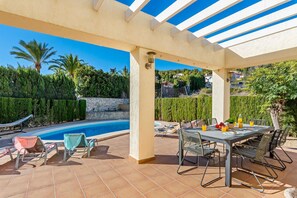 A covered outdoor area with a pool, patio furniture, and a table set for dining.