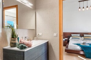 A modern bathroom with a large mirror, a sink, and a potted plant.
