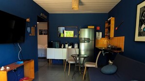 Un espacio habitable compacto con kitchenette, comedor y zona de estar.