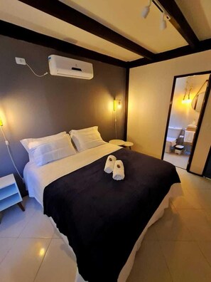 Une chambre d’hôtel équipée d’un lit, d’une table de chevet, d’un miroir et d’un climatiseur fixé au mur.
