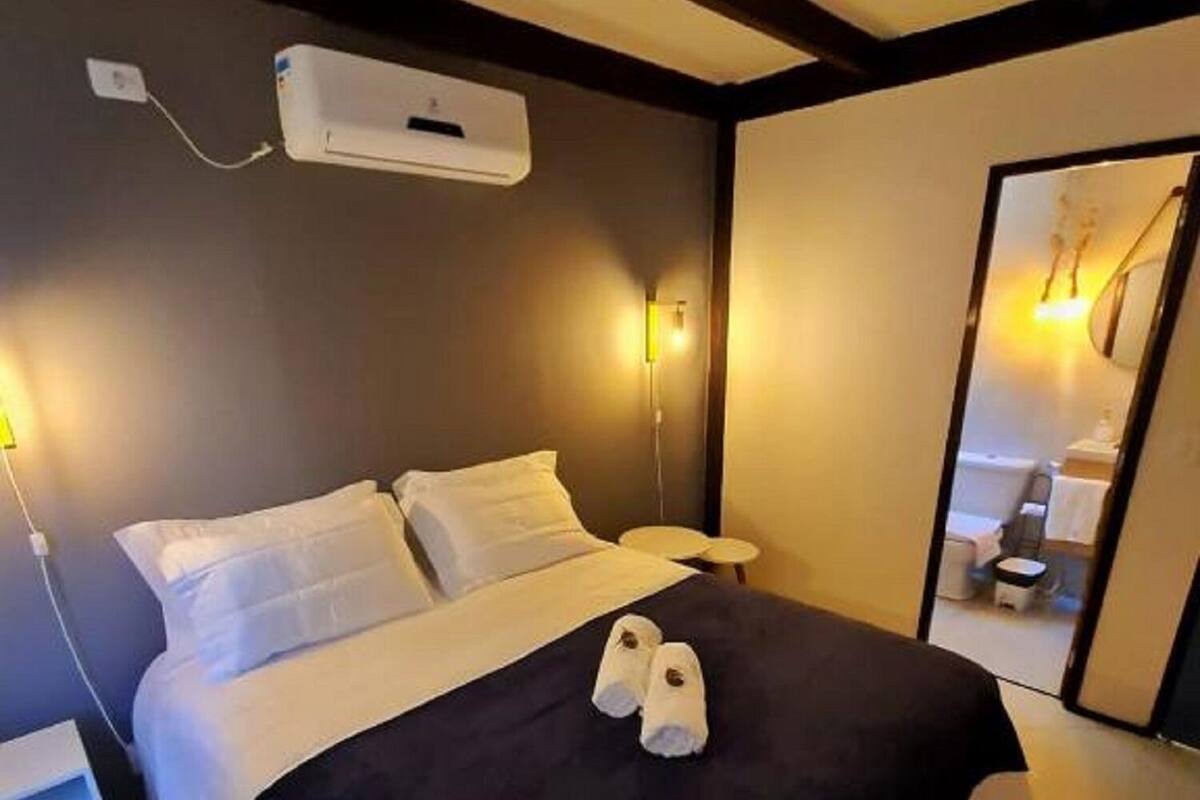 Ein Hotelzimmer mit Bett, Nachttischen, einem Spiegel und einer Wand-Klimaanlage.