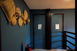 Un couloir aux murs bleus, deux portes portant les numéros 4 et 5, et un extincteur posé sur le sol.