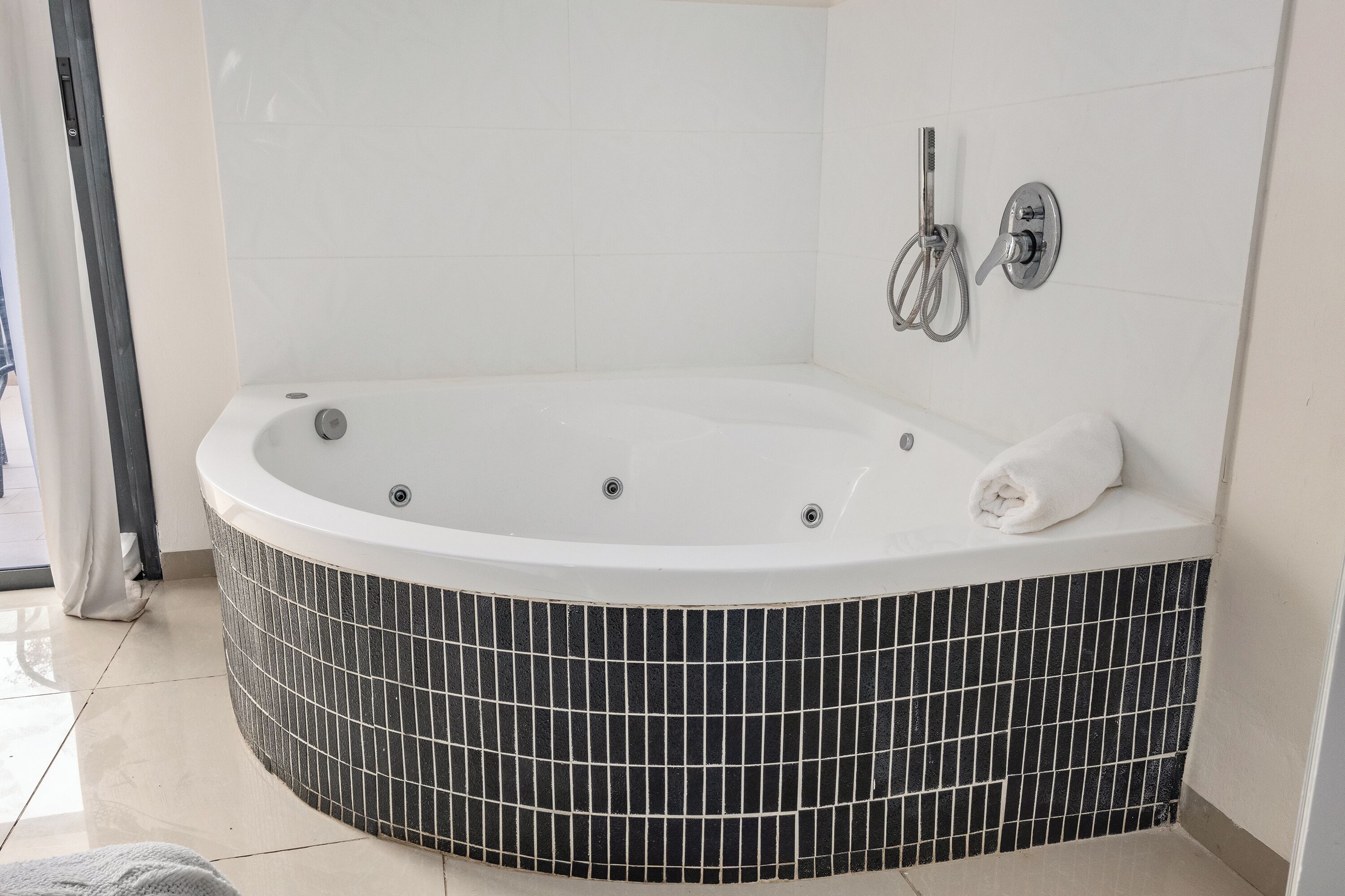 Een moderne badkamer met een vrijstaand bad, een handdoekhouder en een douchekop.