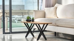 Una sala moderna con un sofá, una mesa de centro de madera y vistas a un balcón.