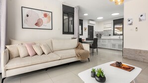 Una sala de estar moderna con un sofá, una mesa de comedor y una cocina al fondo.