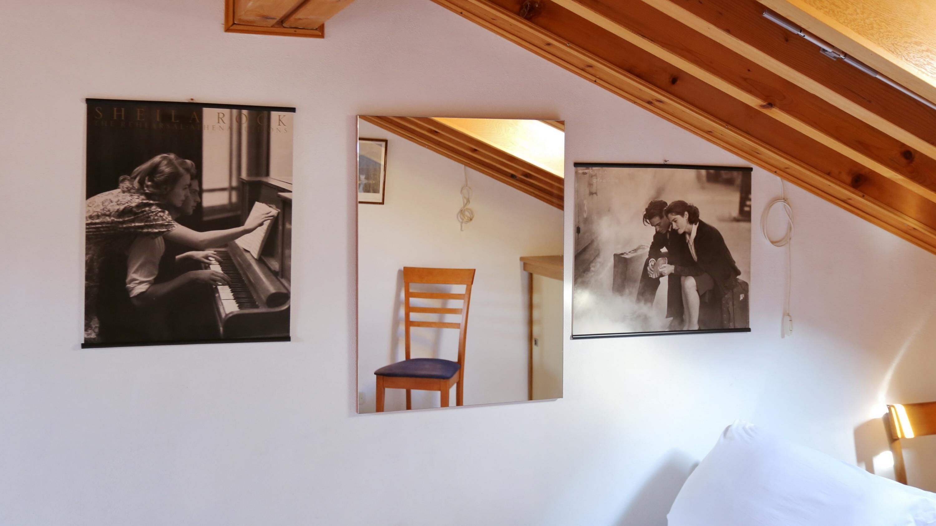 Un dormitorio con una cama, techo de madera y dos fotografías blanco y negro en la pared.