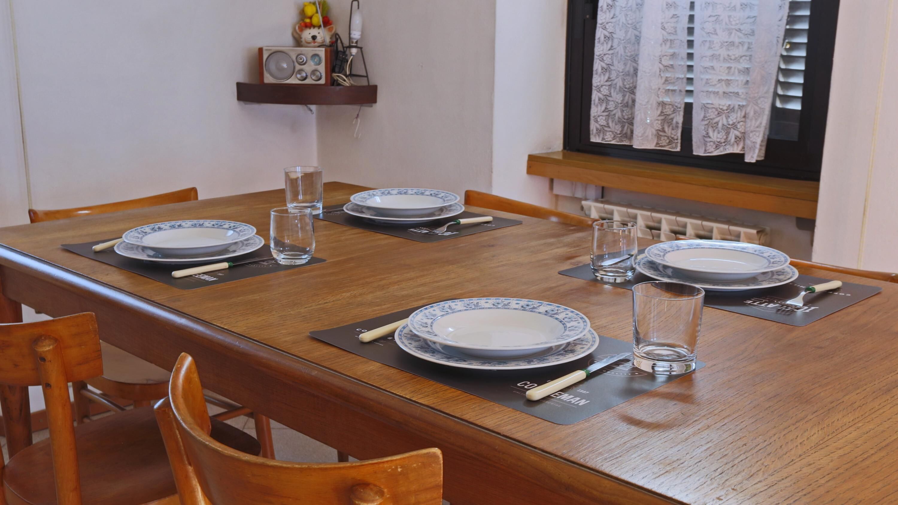 A dining table set with plates, glasses, and cutlery, with chairs around it.