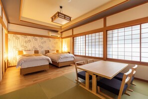 A traditional Japanese-style room with two beds, a table, and tatami flooring.