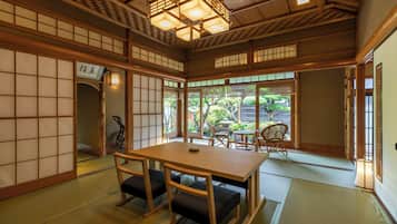 A traditional Japanese room with tatami flooring, a low table with cushions, and sliding doors.