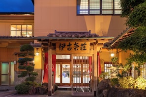 Perinteinen japanilainen rakennus, jossa on puinen sisäänkäynti ja kyltti, jossa on japaninkielisiä merkkejä.