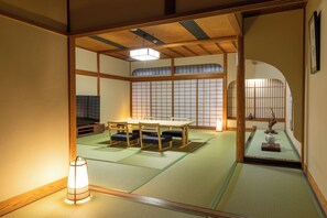 A traditional Japanese room with tatami flooring, a low table, and a television.