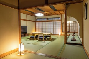 Una habitación japonesa tradicional con suelo de tatami, una mesa baja y un televisor.