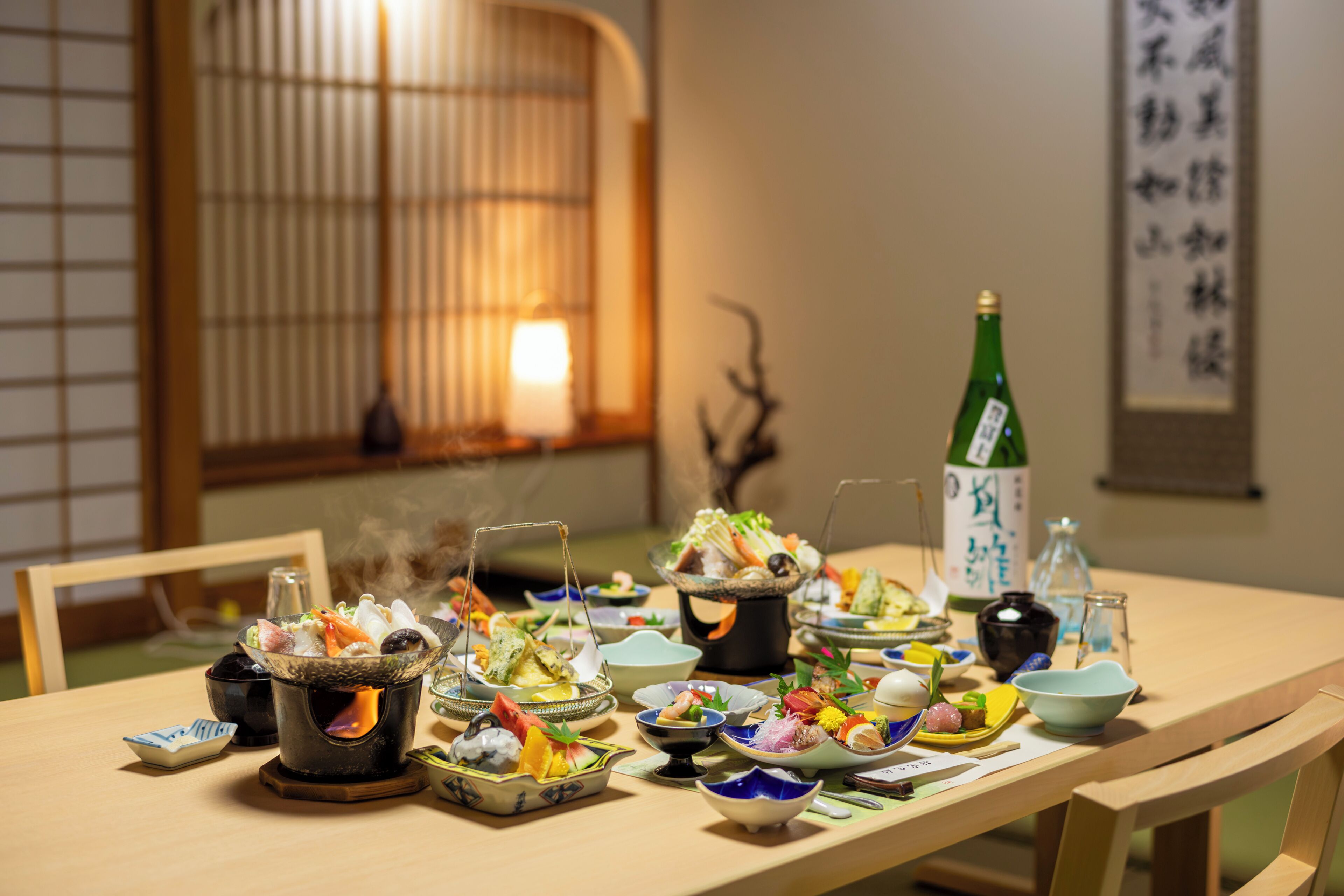 A dining table with various dishes and a teapot, set in a room with traditional decor.