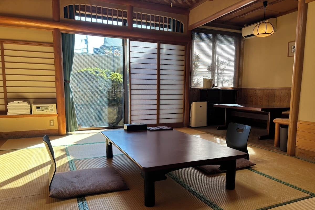 Um quarto japonês tradicional com tatames, uma mesa baixa e portas corrediças.