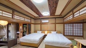 A traditional Japanese-style room with two beds, wooden flooring, and a sliding door leading to a garden.