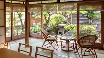 A traditional Japanese room with tatami flooring, a low table, and four bamboo chairs.
