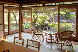 Una habitación tradicional japonesa con suelo de tatami, una mesa baja y cuatro sillas de bambú.