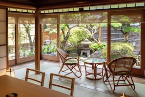 A traditional Japanese room with tatami flooring, a low table, and four bamboo chairs.