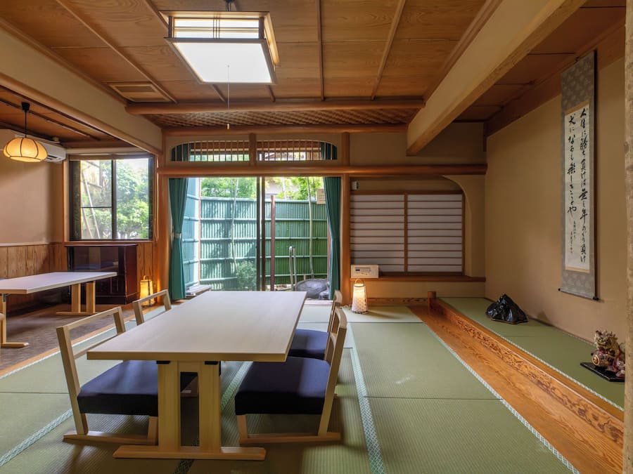 A traditional Japanese room with tatami flooring, a low table with cushions, and a sliding door.