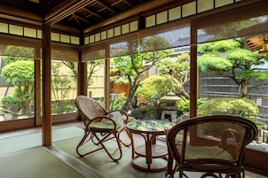 A traditional Japanese room with tatami flooring, a low table, and two chairs.