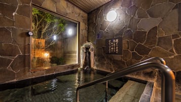 A stone-walled interior with a wooden staircase leading to a lower level.