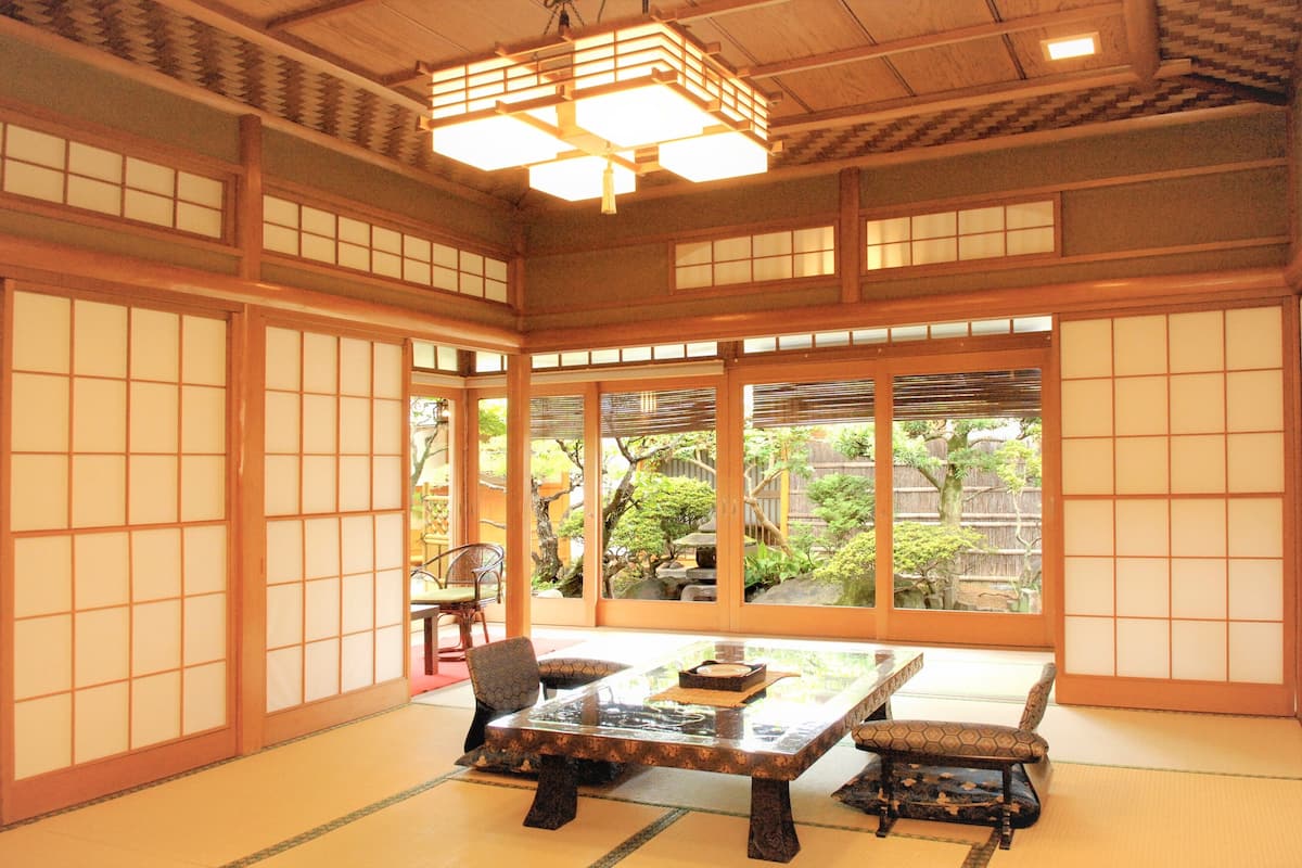Um quarto japonês tradicional com tatames, uma mesa baixa e portas corrediças.