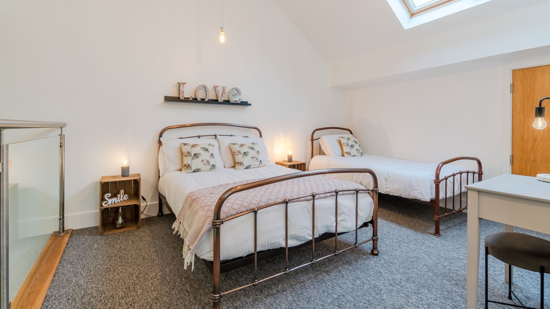 Ein Schlafzimmer mit zwei Betten, einem Schreibtisch und einem Regal mit Dekoration.