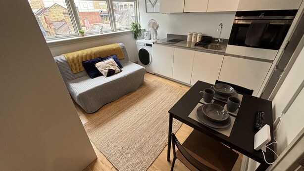 A compact kitchen with a dining area, a sofa, and a view of the city through large windows. - Sleeps 2 Studio -central Croydon London -wifi & Tv (Croydon)