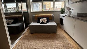 A compact room with a bed, a washing machine, and a window with a view of buildings. - Sleeps 2 Studio -central Croydon London -wifi & Tv (Croydon)