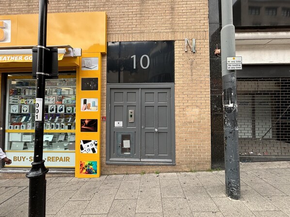 Un escaparate con un letrero que dice 'BUY'S REPAIR', un letrero que indica 'PRODUCTOS DE CUERO' y una puerta con el número 10.