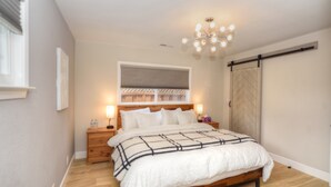 Camera da letto con un letto in legno, lampade sui comodini, una luce a soffitto e una porta a griglia scorrevole.
